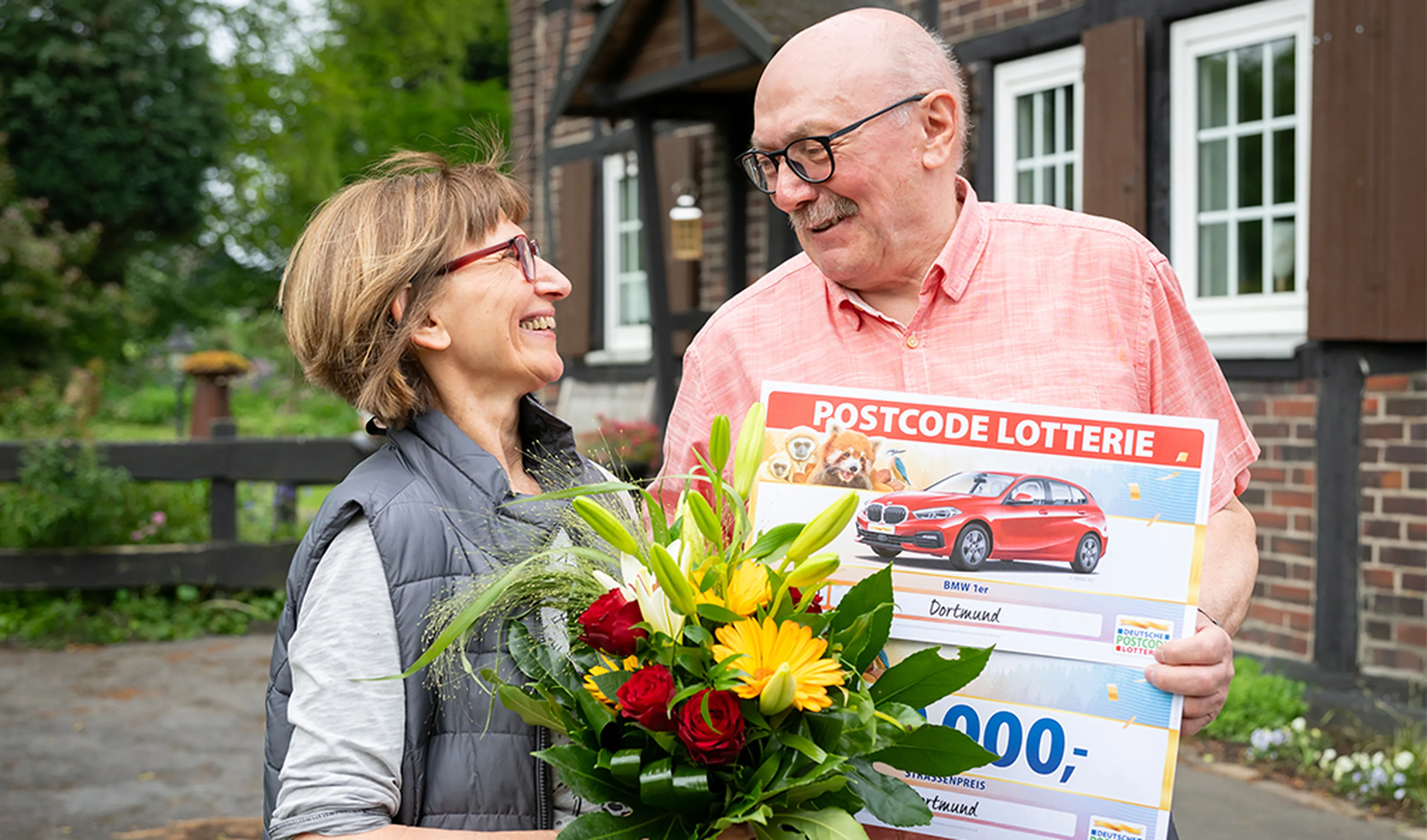 Der Straßenpreis Gewinner in Dortmund freut sich über 10.000 Euro und einen BMW 1er von der Deutschen Postcode Lotterie
