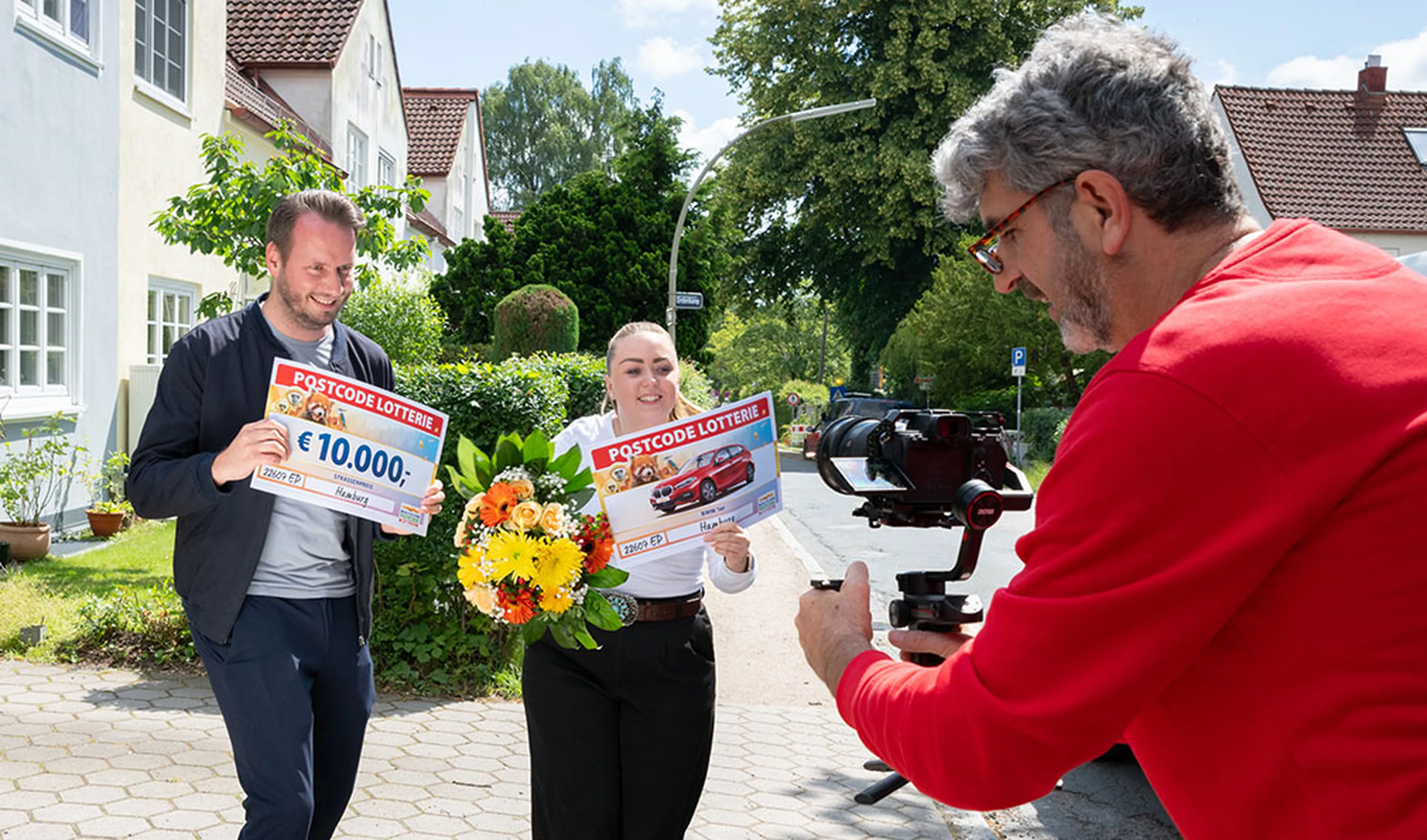 Die Gewinnerin beim Straßenpreis der Deutschen Postcode Lotterie jubelt über 10.000 Euro und einen BMW 1er